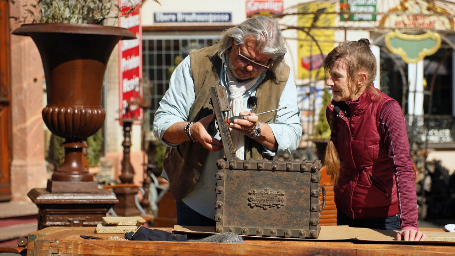 Roman Runkel und Martina Simontowski mit einer kleinen, braunen, viktorianischen Kassette.
