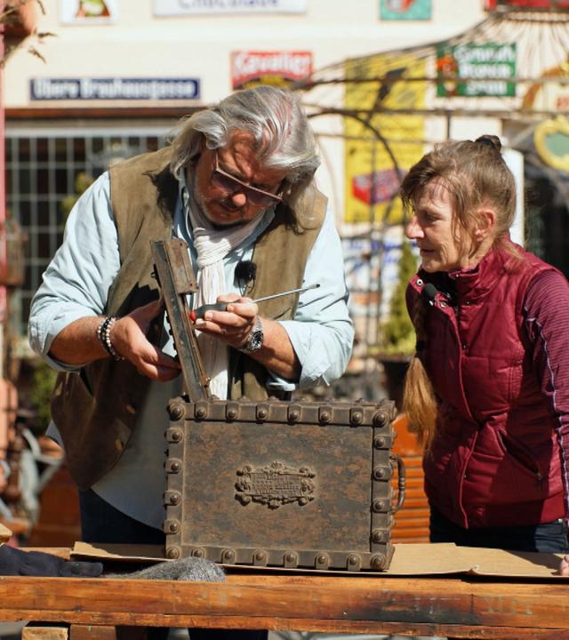 Roman Runkel und Martina Simontowski mit einer kleinen, braunen, viktorianischen Kassette.