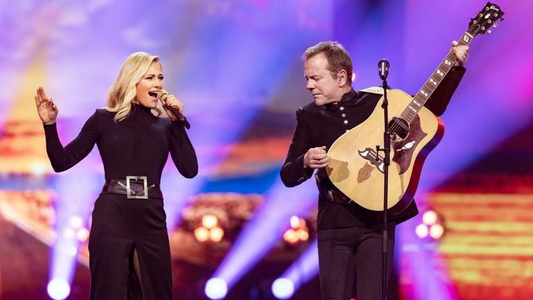 "Die Helene Fischer Show": Helene Fischer und Kiefer Sutherland stehen auf der Bühne und musizieren gemeinsam. Helene Fischer singt in ihr Mikrofon, Kiefer Sutherland spielt dazu Gitarre.