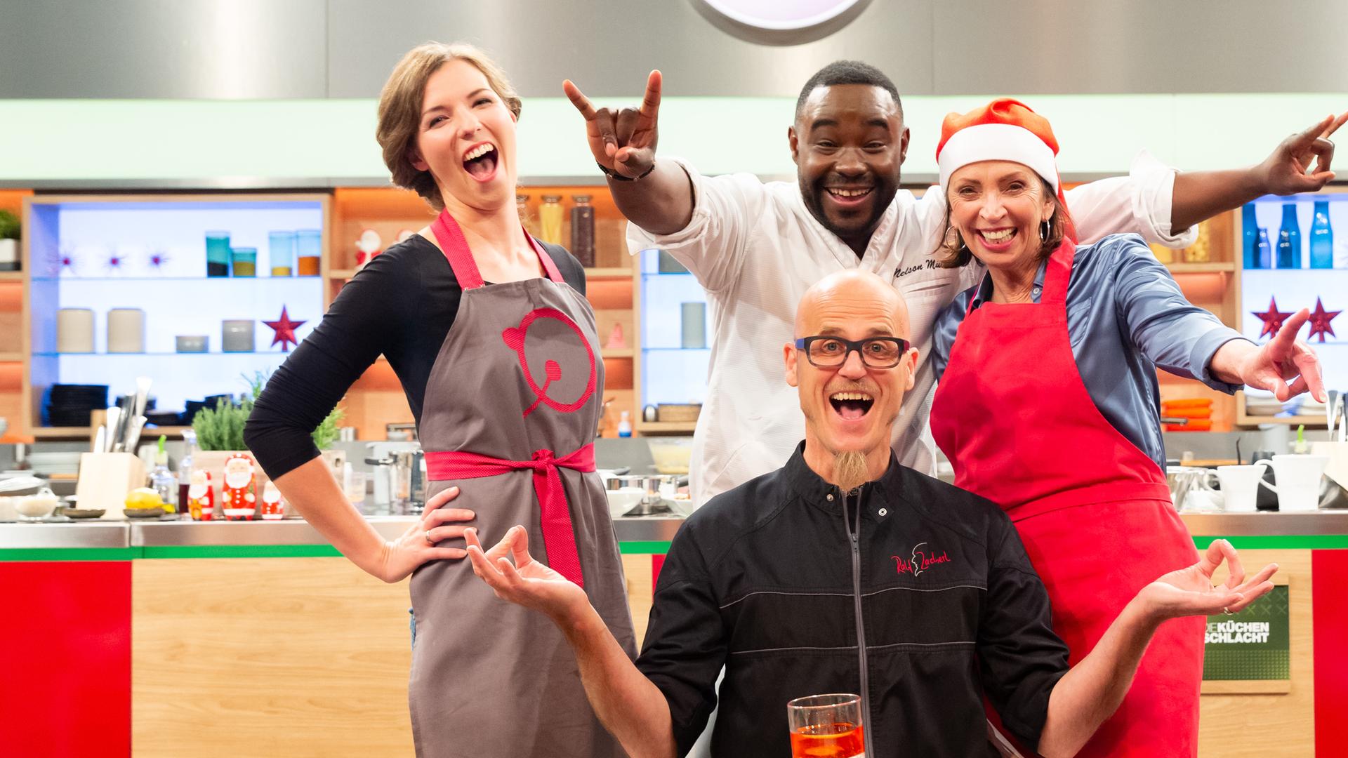 Die Küchenschlacht vom 12. Dezember 2018: Nelson Müller, Ralf Zacherl und zwei Kandidatinnen lächeln in die Kamera.