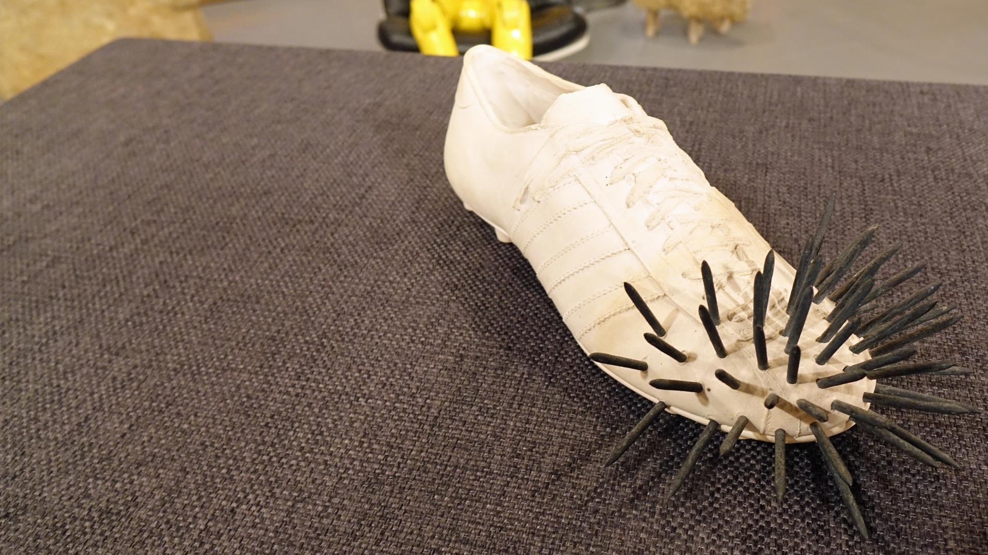 Ein Gipsguss in Form eines Fußballschuhs mit Nägeln von Uecker und Fongi