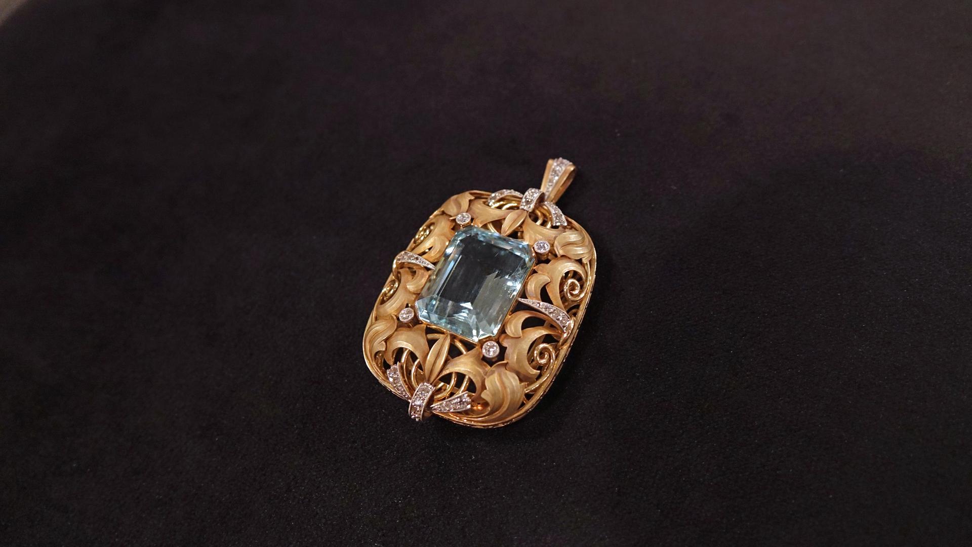 Ein filigran gearbeiteter Goldanhänger mit Diamanten und einem blauen Aquamarin in der Mitte