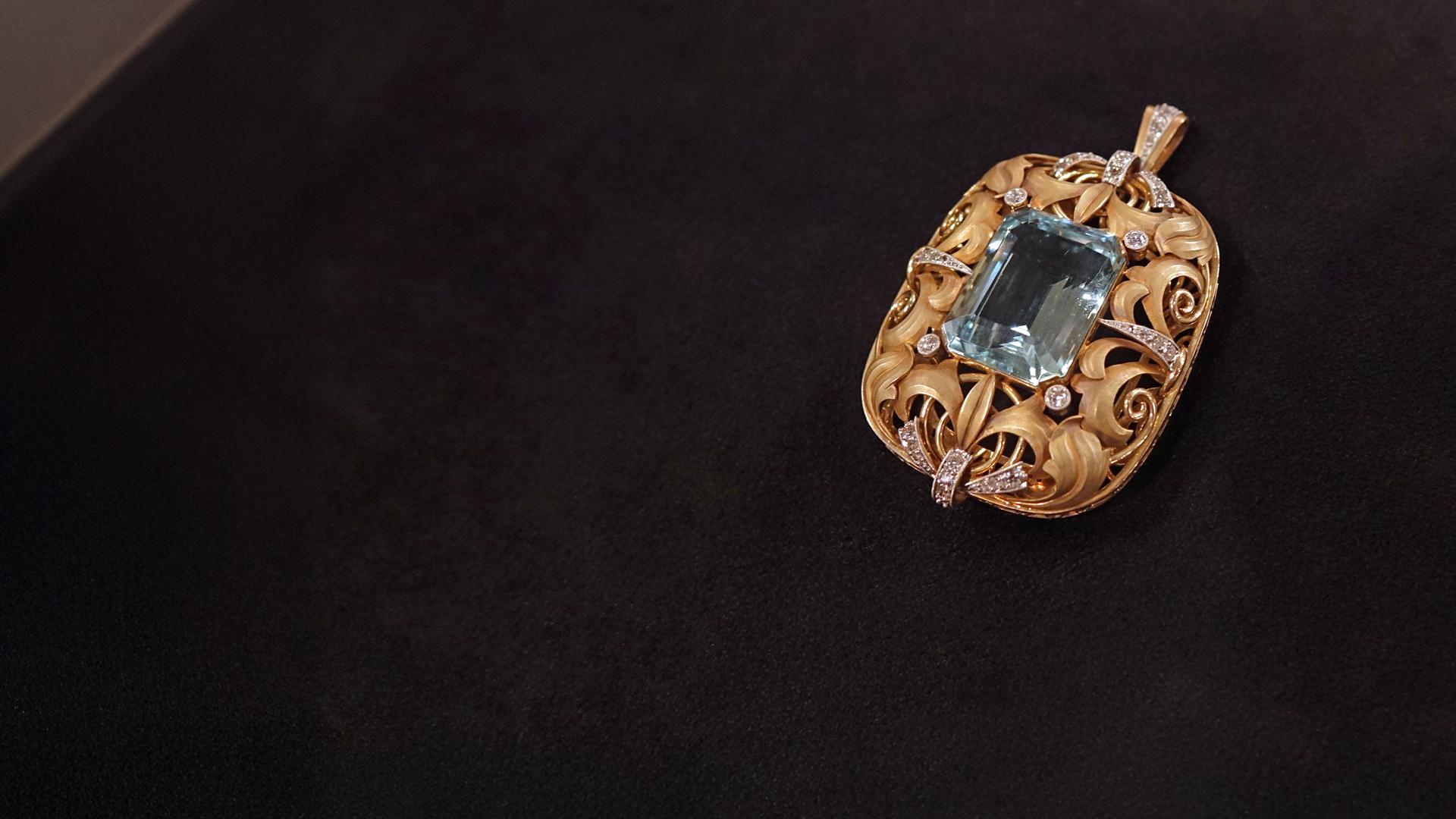 Ein filigran gearbeiteter Goldanhänger mit Diamanten und einem blauen Aquamarin in der Mitte