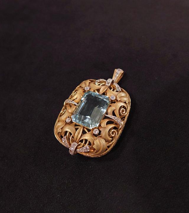 Ein filigran gearbeiteter Goldanhänger mit Diamanten und einem blauen Aquamarin in der Mitte