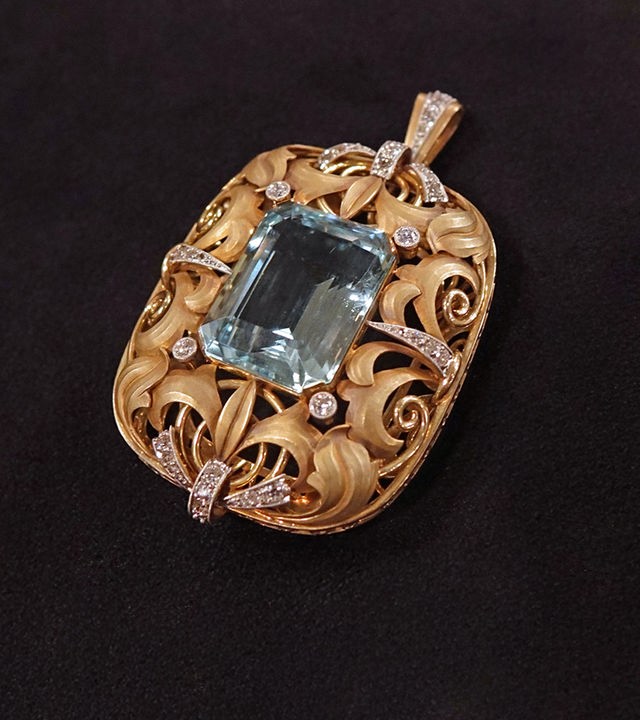 Ein filigran gearbeiteter Goldanhänger mit Diamanten und einem blauen Aquamarin in der Mitte