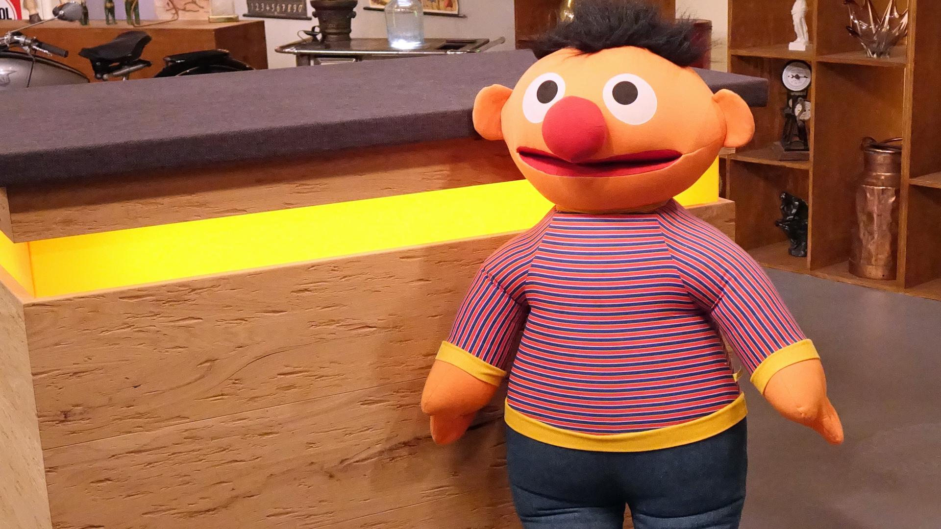 "Ernie" aus der Sesamstrasse als große Stoffpuppe vor dem Tresen im Expertisenraum.