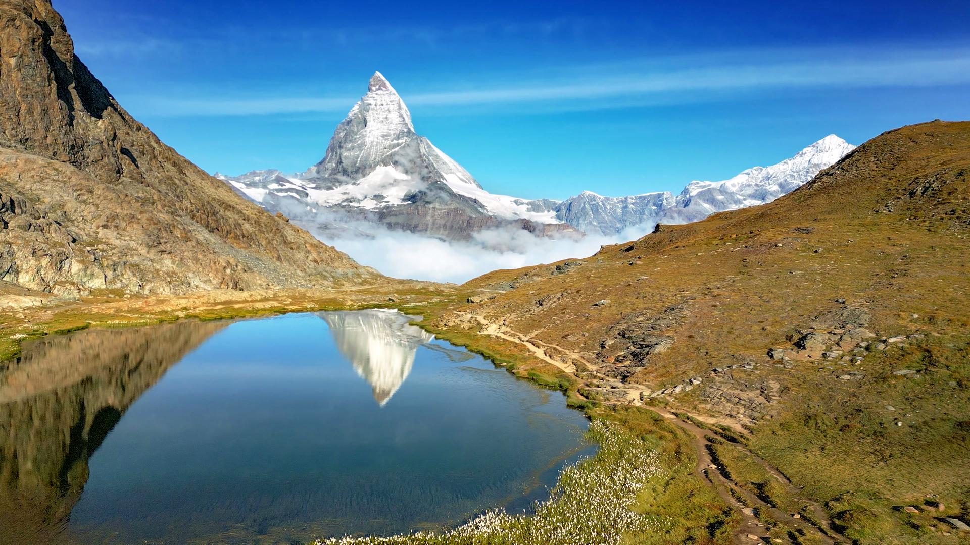 Ein Bergpanorama. Im Vordergrund ein See.