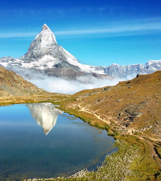 Ein Bergpanorama. Im Vordergrund ein See.