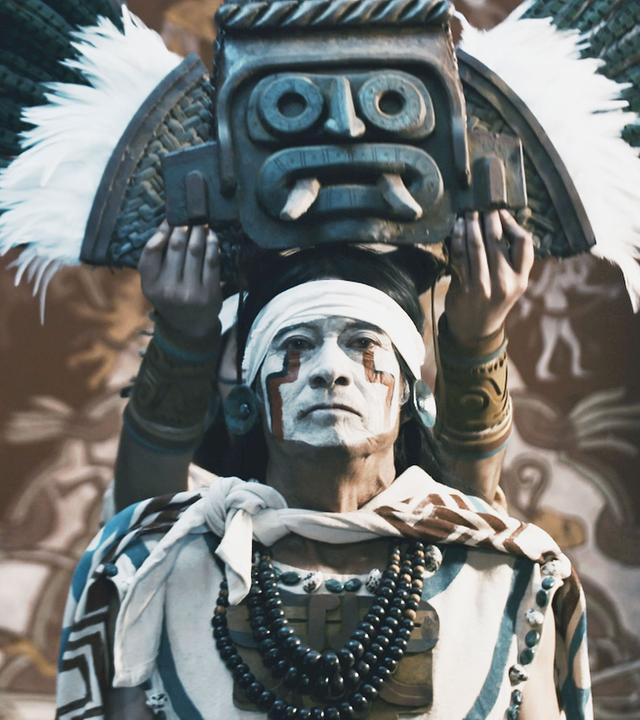  Ein Oberhaupt der Teotihuacán-Zivilisation mit Kriegsbemalung und rituellem Gewand, bekommt eine Art gefiederte Krone aufgesetzt.