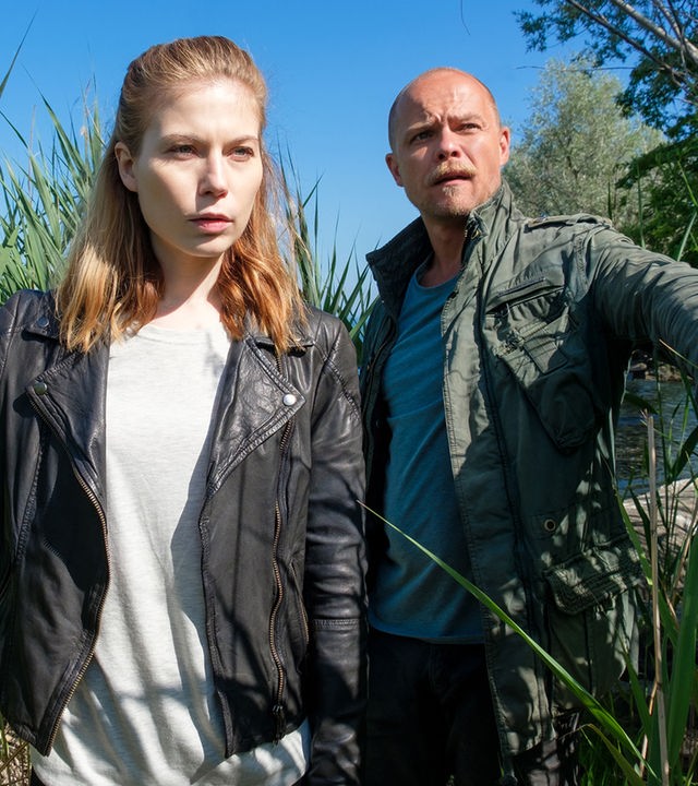 „Die Toten vom Bodensee - Die Meerjungfrau“: Zeiler (Nora Waldsätten) und Oberländer (Matthias Koeberlin) schieben Schilf zur Seite und sehen angespannt nach vorne.