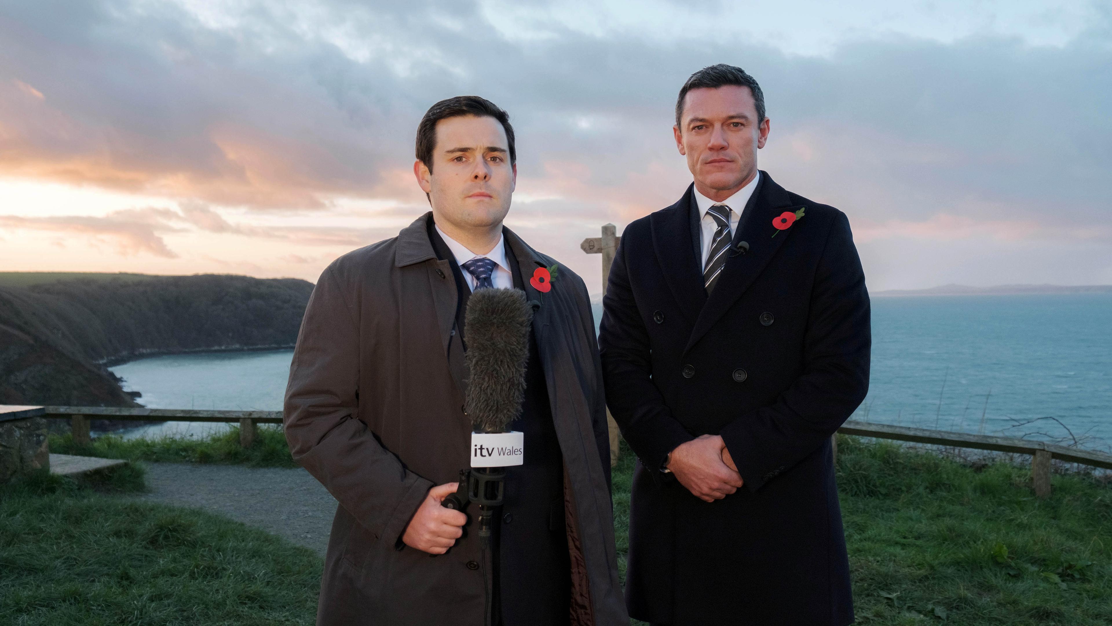 "Die Pembrokeshire Morde (1)": DCS Steve Wilkins (Luke Evans) und Reporter Jonathan Hill (David Fynn) stehen nebeneinander an der Küste und sehen ernst in die Kamera.