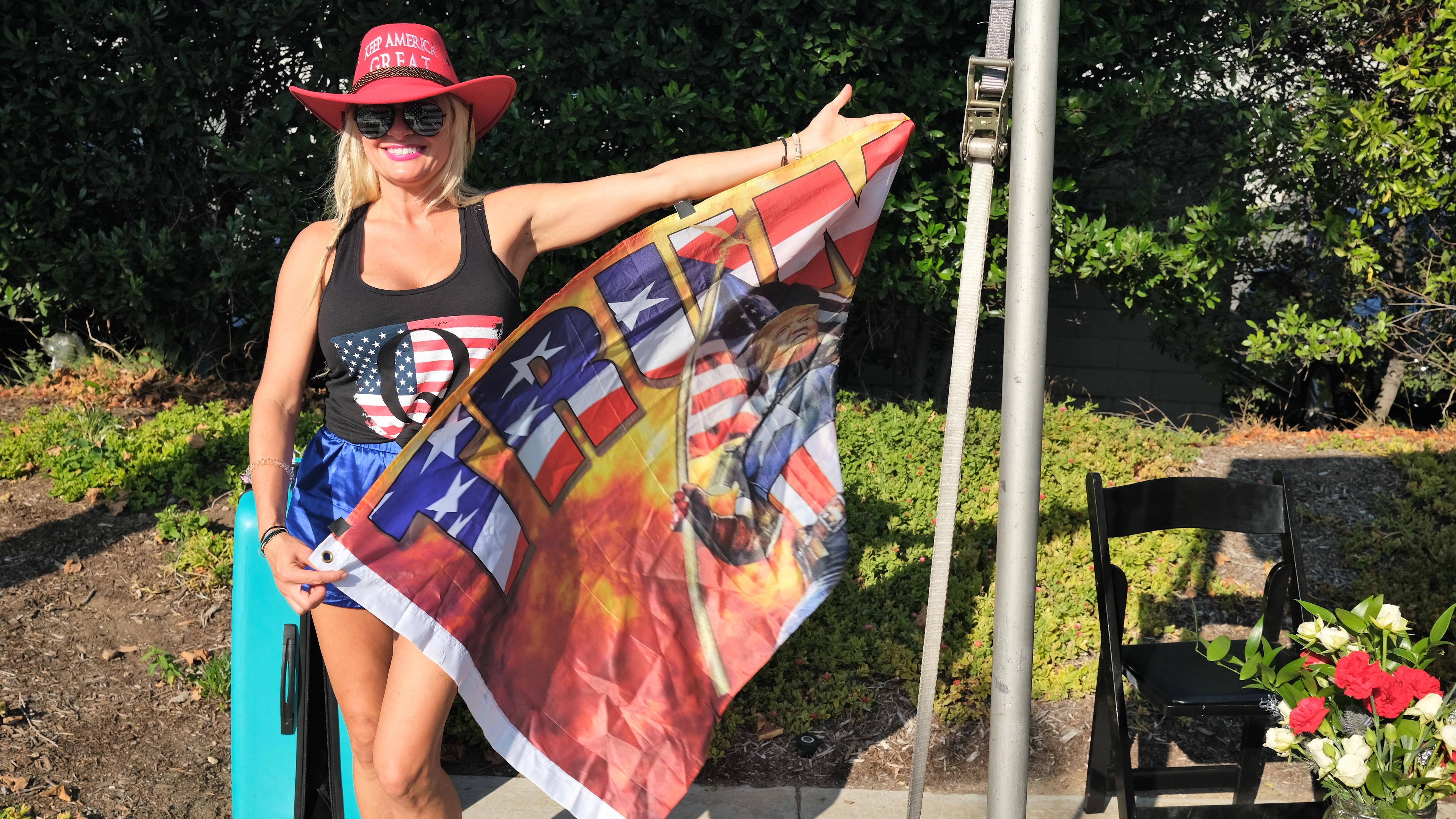 Eine Frau posiert mit Trump-Flagge in einem Garten.
