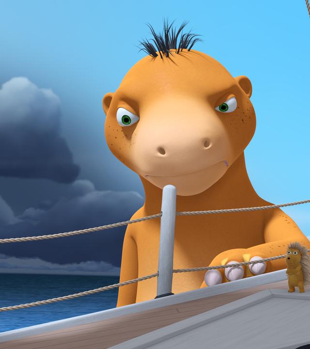 Der Wasserdrache Amadeus steht neben Chef's Schiff im Wasser. Er sieht unzufrieden aus. Auf dem Schiff stehen Matilda, Xiexie, Oskar und Kokosnuss.