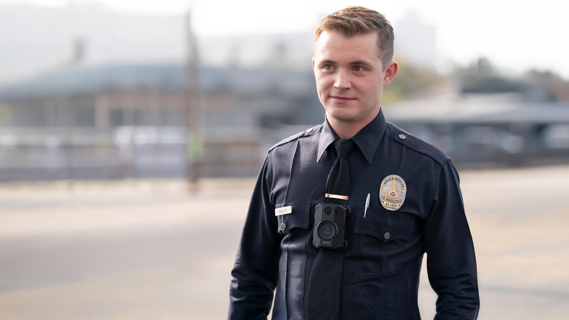 "The Rookie - Die Rückkehr": Draußen auf einem Gelände steht Rookie Seth Ridley (Patrick Keleher) und blickt nach vorn. Er trägt eine dunkle Polizeiuniform.