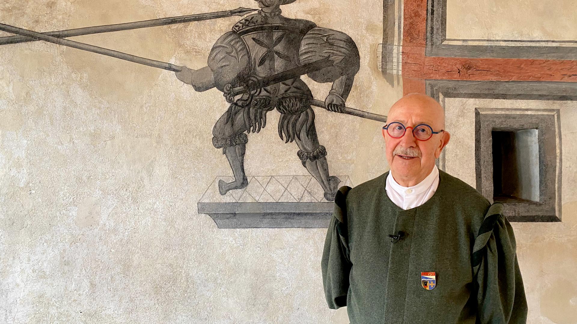 Älterer Herr in Tracht vor Wandgemälde 