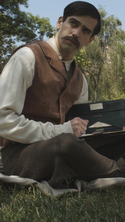 "Die Science-Fiction-Propheten: H. G. Wells: Zeitmaschine und Krieg der Welten": Der junge H.G. Wells (Darsteller unbekannt) sitzt in einem Park und schreibt. Neben ihm liegt ein Fahrrad im Gras.