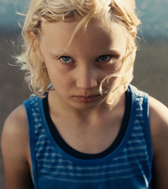 "Die Tochter":  Luca (Helena Zengel) in einem ärmellosen T-Shirt steht am Strand und schaut mit ernstem Blick nach oben.
