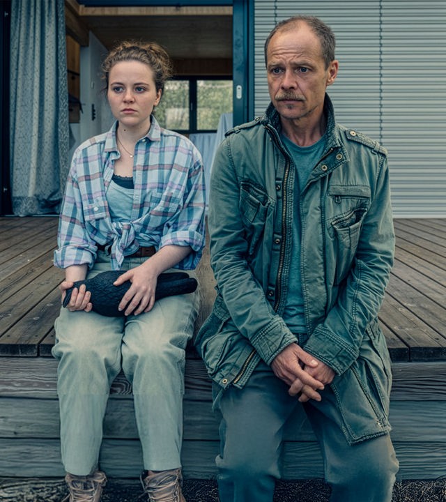 "Die Toten vom Bodensee - Das Geisterschiff": Lenka Bergdorf (Alice Prosser) und Micha Oberländer (Matthias Koeberlin) sitzen nebeneinander auf einem Bootssteg. Lenka Bergdorf hält eine Figur in der Hand.