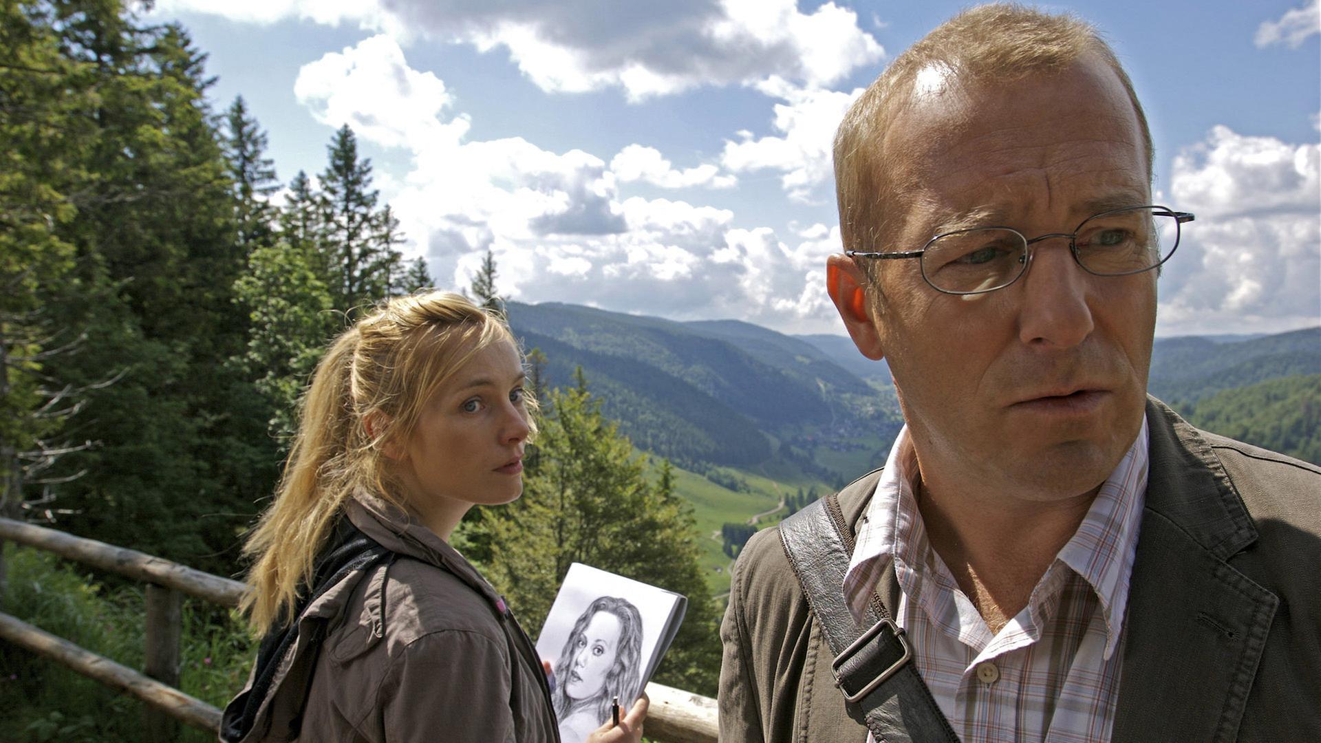 "Die Toten vom Schwarzwald": Matthias Auerbach (Heino Ferch) und Inka (Nadja Uhl) stehen zusammen auf dem Hochplateau des Feldberges im Schwarzwald. Inka hält ein gezeichnetes Porträt von einer Frau in den Händen.