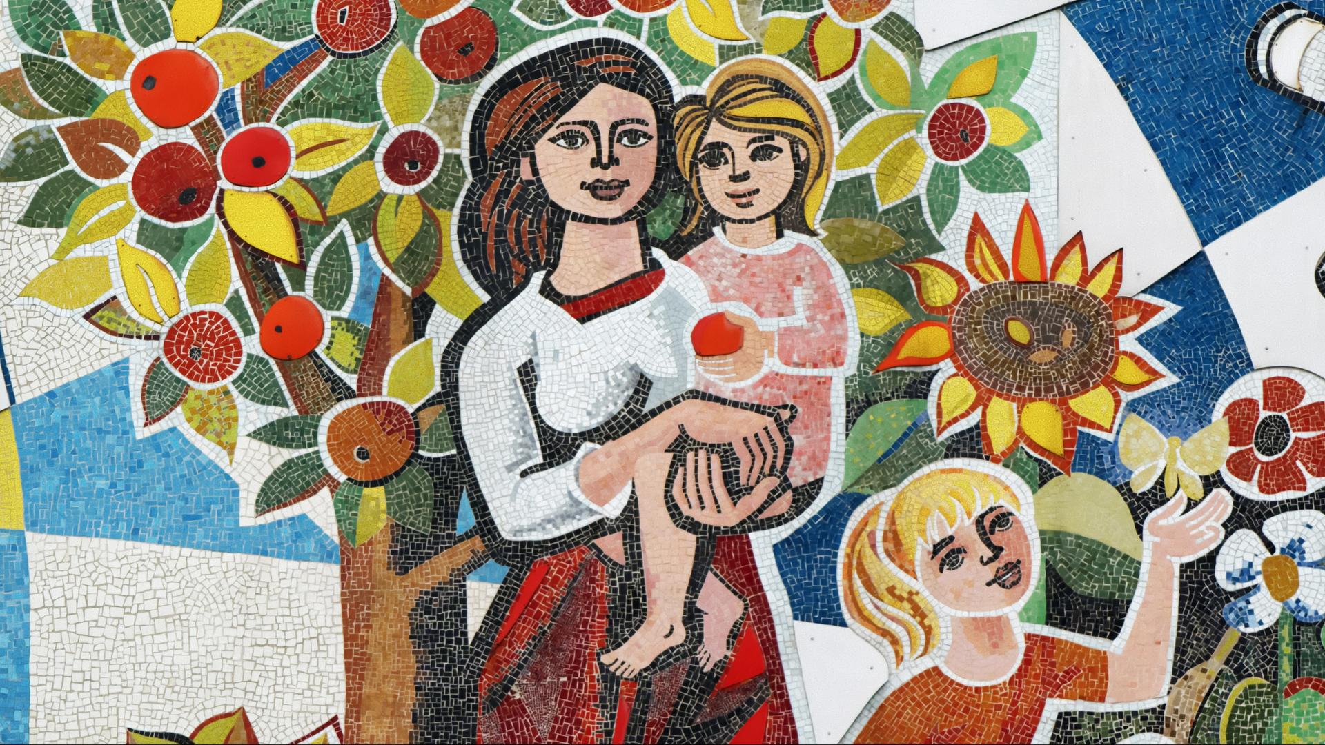 Mosaik mit einer Frau, die ein Kind im Arm hält, während ein weiteres Kind vor Blumen und einem Schmetterling steht; im Hintergrund ein Apfelbaum und Sonnenblumen.