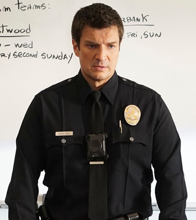 "The Rookie - Die Versuchung": Officer John Nolan (Nathan Fillion) steht vor einem Rednerpult. Und blickt in die Richtung seiner zuhörenden Kollegen. Im Hintergrund ein Whiteboard mit handschriftlichen Erörterungen.