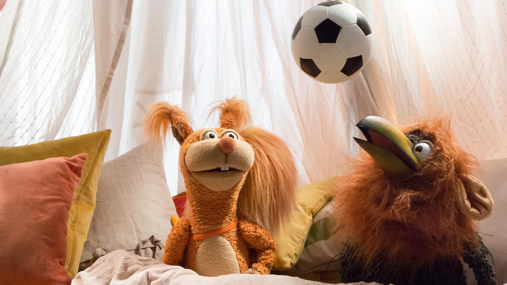Ella und Rudi mit Löwenmähne hocken in der Kuschelecke. Beider schauen nach oben zum Fußball, der über ihnen hängt.