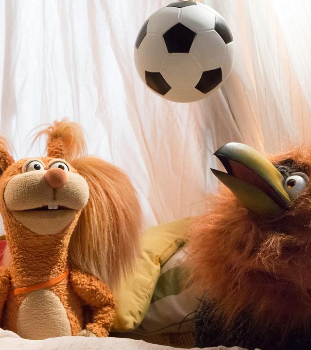 Ella und Rudi mit Löwenmähne hocken in der Kuschelecke. Beider schauen nach oben zum Fußball, der über ihnen hängt.