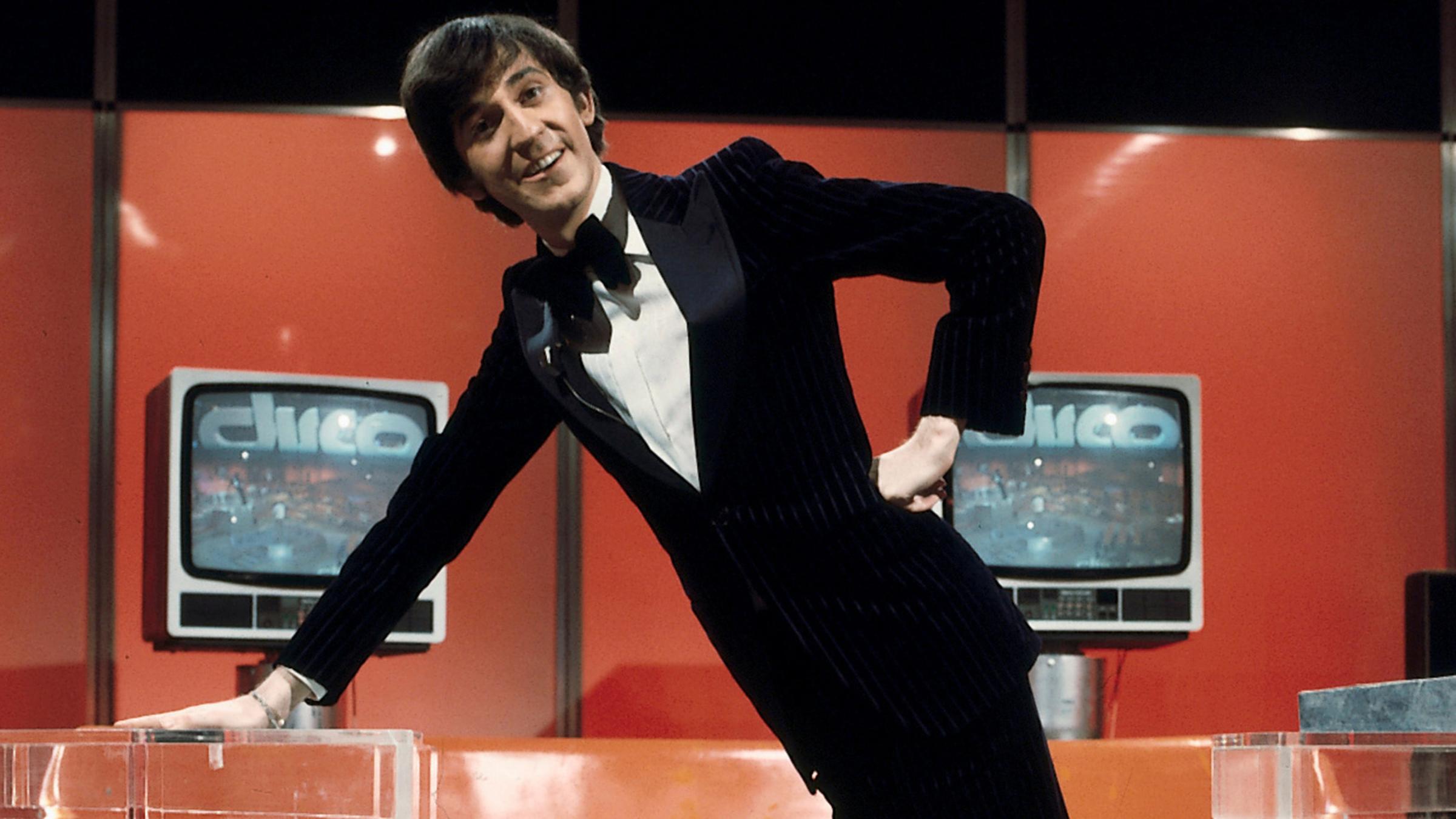 Ilja Richter in schwarzem Smoking in der berühmten Studiodekoration.