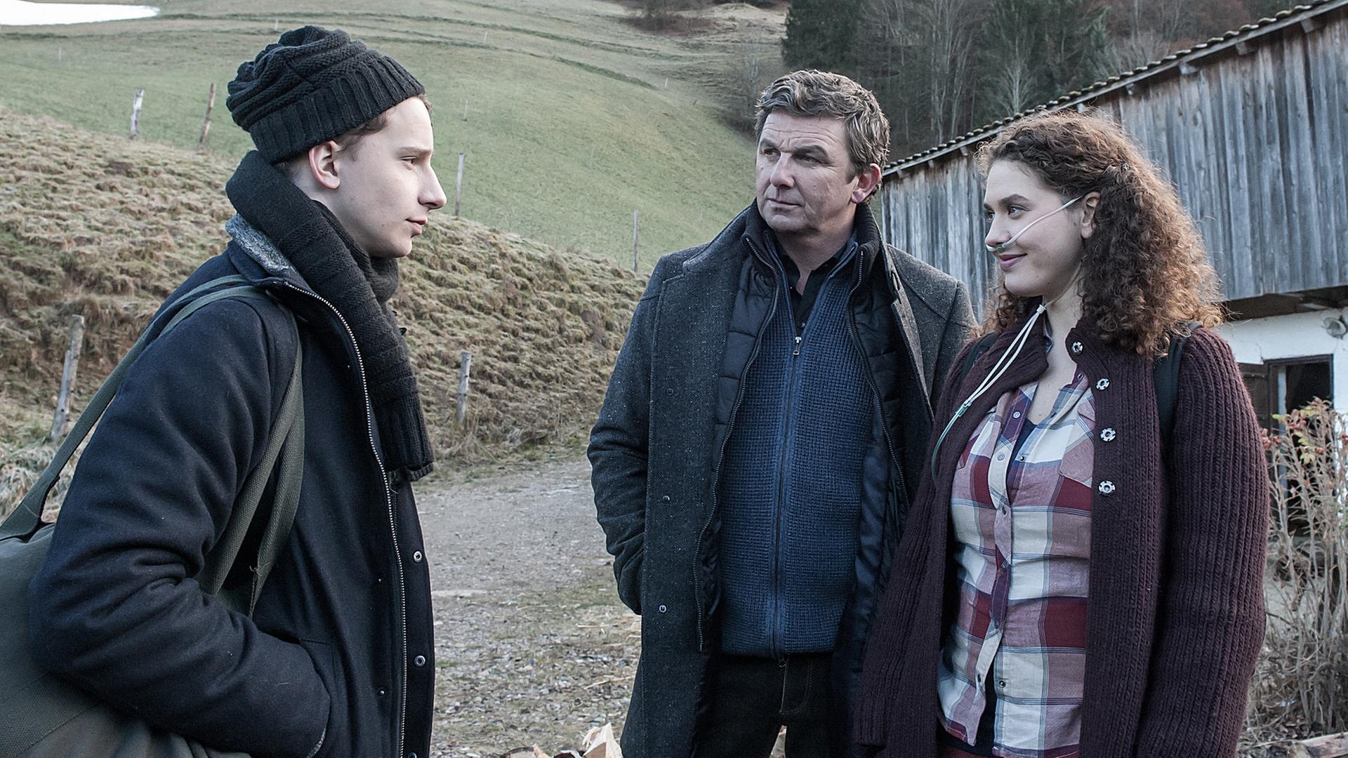 "Der Bergdoktor - Die Zeit, die bleibt (1)": Martin Gruber (Hans Sigl) verfolgt das Gespräch zwischen David (Jonathan Berlin) und Lisa (Fanny Krausz). Sie trägt einen Beatmungsschlauch in der Nase.