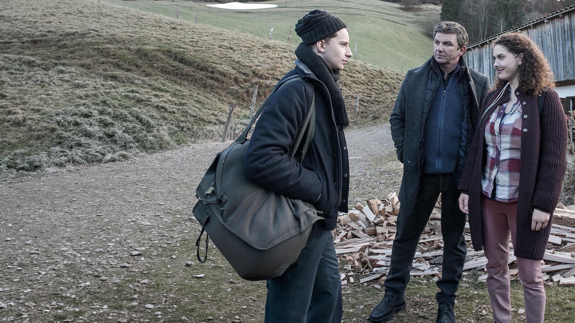 "Der Bergdoktor - Die Zeit, die bleibt (1)": Martin Gruber (Hans Sigl) verfolgt das Gespräch zwischen David (Jonathan Berlin) und Lisa (Fanny Krausz). Sie trägt einen Beatmungsschlauch in der Nase.