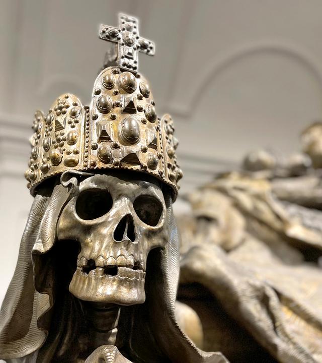 Aus Bronze gegossener Totenkopf mit Reichskrone auf einem Sarkophag