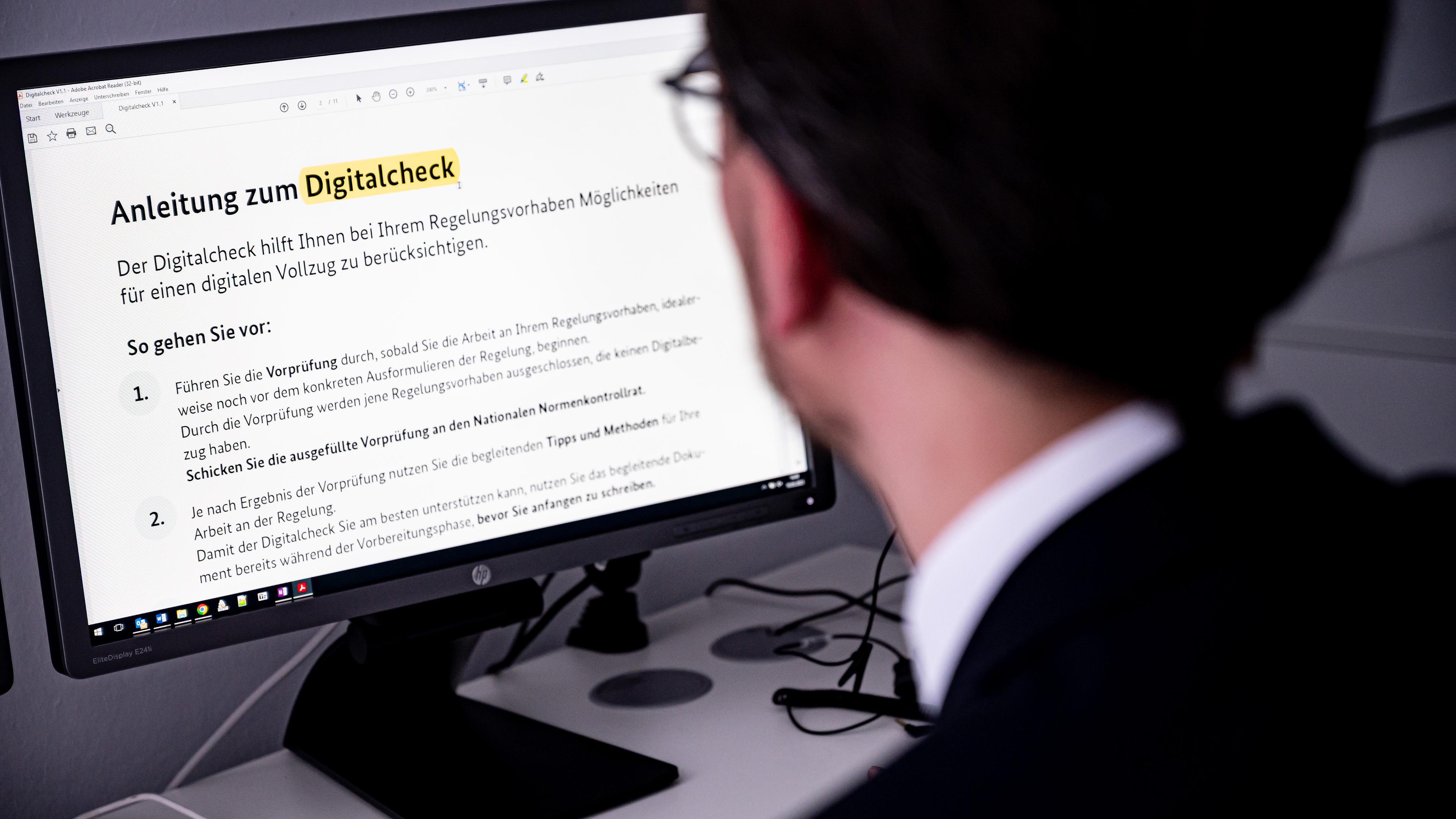 Illustration: Ein Mitarbeiter des Justizministeriums schaut auf einen Bildschirm mit dem Wort Digitalcheck, aufgenommen am 10.03.2023