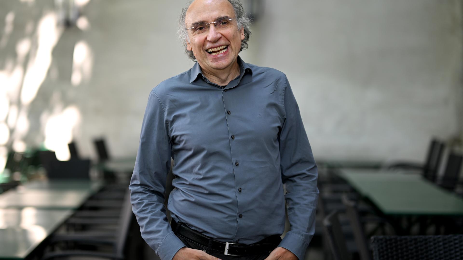 Porträtfoto eines Mannes mit kurzen lockigen graumelierten Haaren, Halbglatze und Brille.