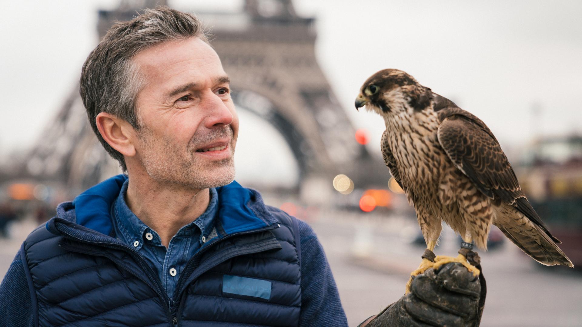 Dirk Steffens mit einem Falken vor dem Eiffelturm