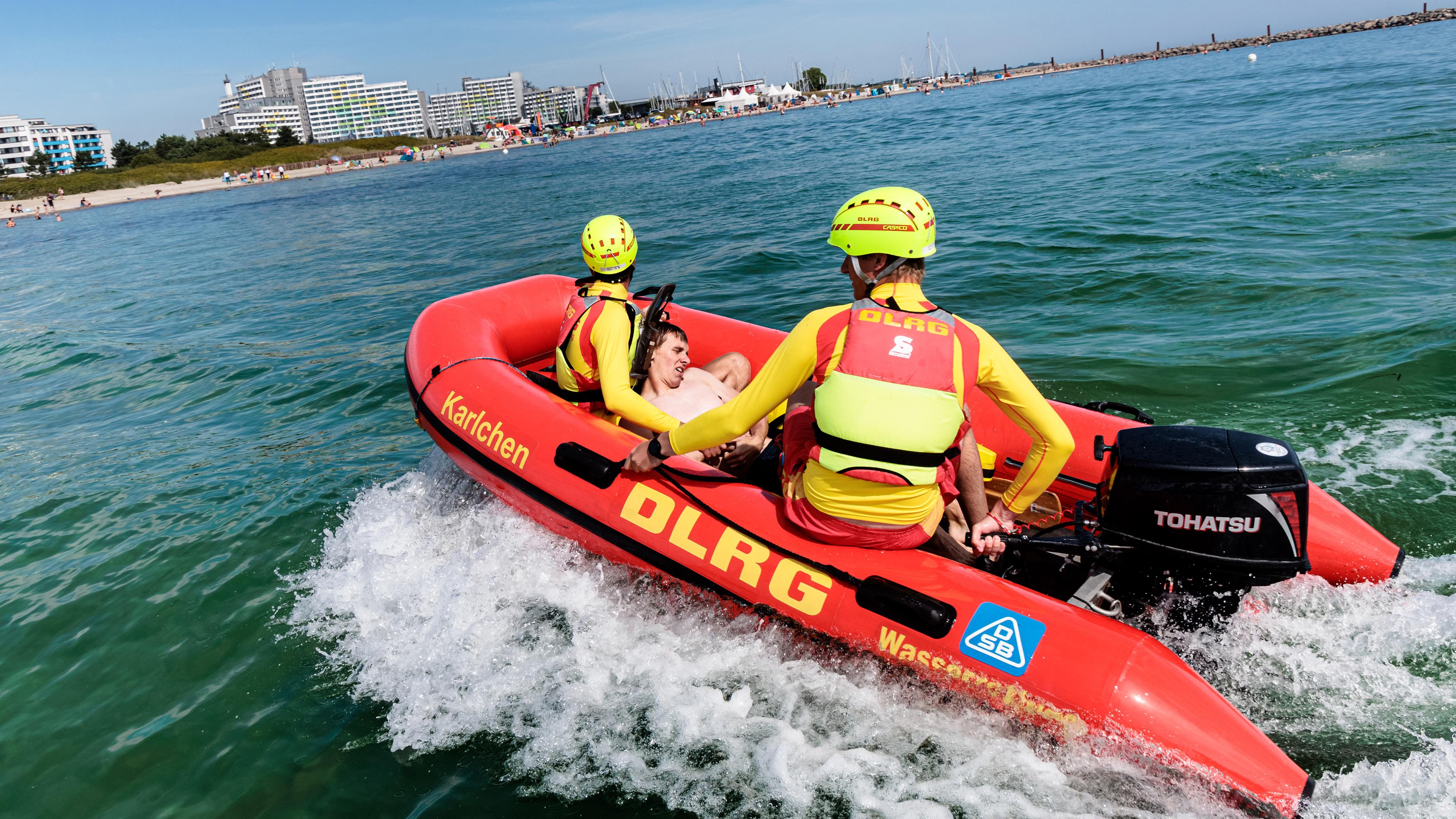Rettungsschwimmer der Deutschen Lebens-Rettungs-Gesellschaft (DLRG) bringen bei einer Übung einen Statisten zurück an den Strand. 