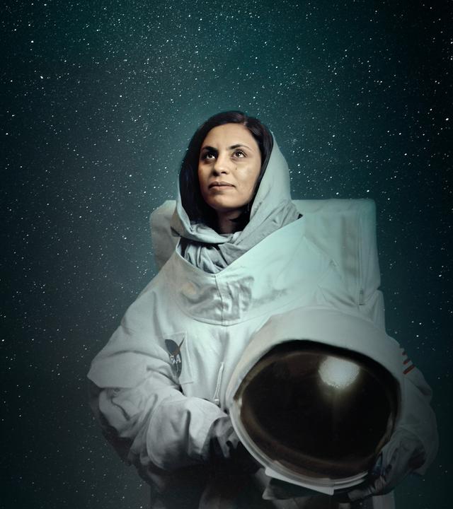Frau im Astronautenanzug blickt nach oben.