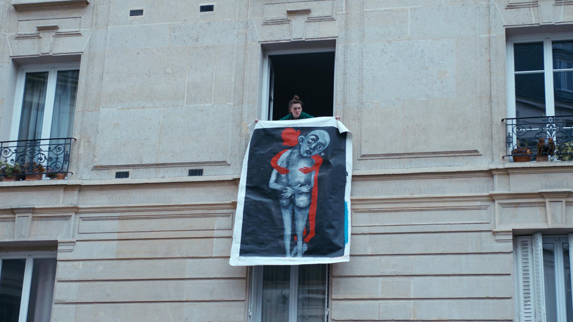 Totale von Frau, die ein großes Bild aus dem Fenster hält.