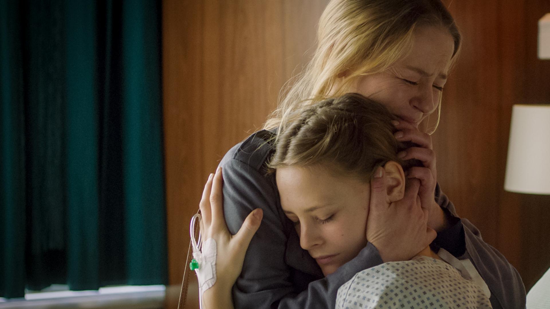 Sabrina hält ihre Tochter Lilly im Arm, die im Krankenbett sitzt.