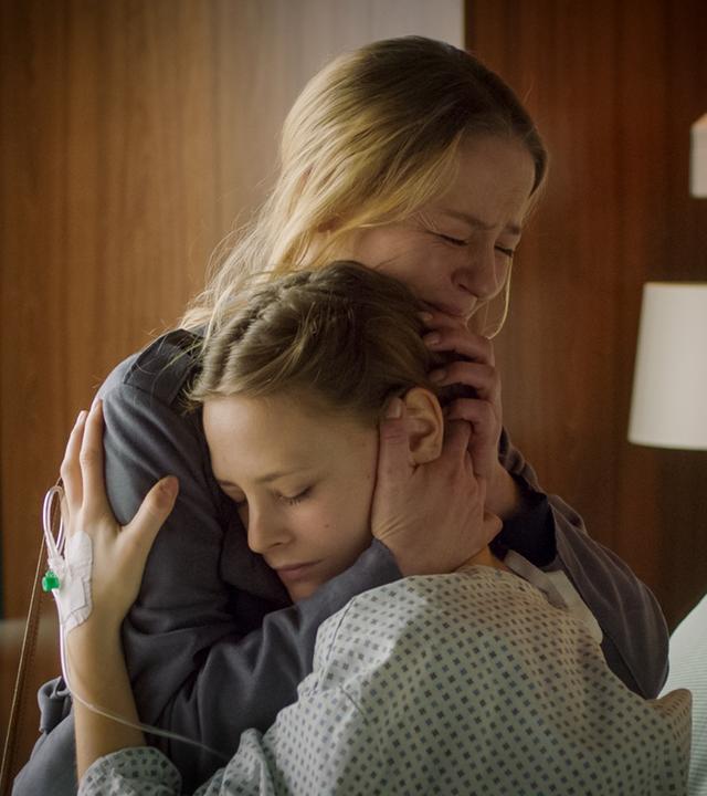 Sabrina hält ihre Tochter Lilly im Arm, die im Krankenbett sitzt.