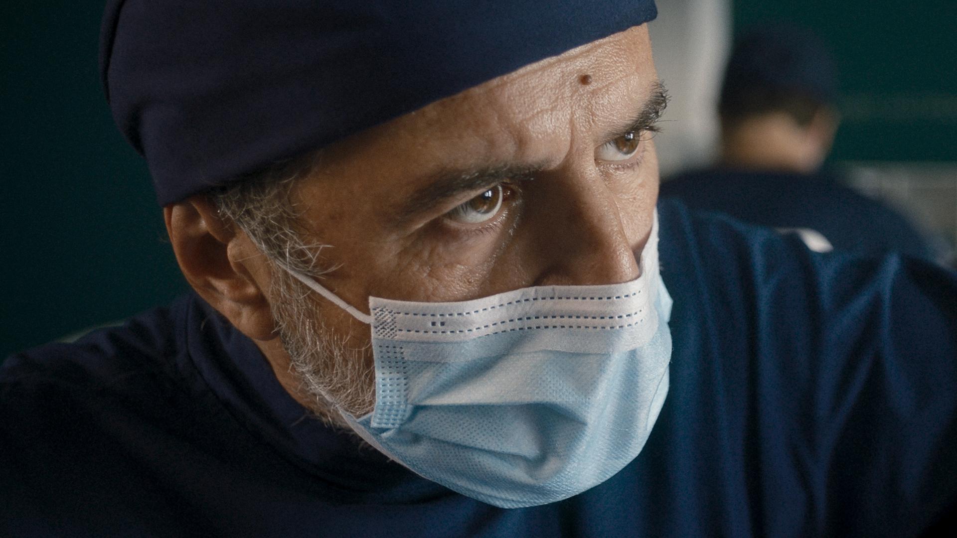 "Doktor Ballouz - Leere Seiten": Großaufnahme von Doktor Ballouz (Merab Ninidze). Er trägt OP-Kleidung sowie einen Mundschutz. Er schaut ganz konzentriert während des Eingriffes.