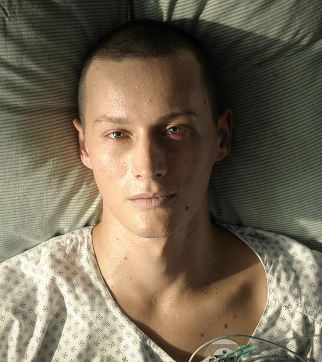 Matti liegt im Krankenbett und wartet auf die rettende Knochenmarkspende. Sein Gesicht ist sehr blass und von Schweißperlen überzogen.