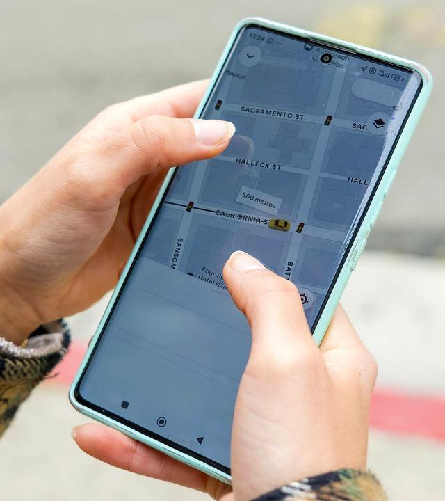 Eine Person hält ein Smartphone in der Hand und benutzt die GPS Navigations App mit Straßenkarte von San Francisco