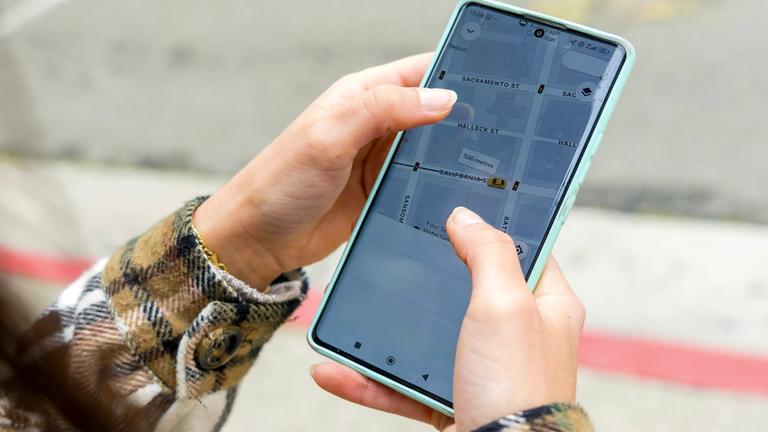 Eine Person hält ein Smartphone in der Hand und benutzt die GPS Navigations App mit Straßenkarte von San Francisco