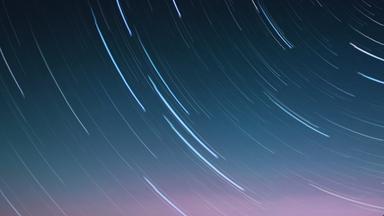 Abstraktes Bild: Zeitrafferaufnahme Sternenhimmel mit Sternenlichtern, die zu Streifen werden