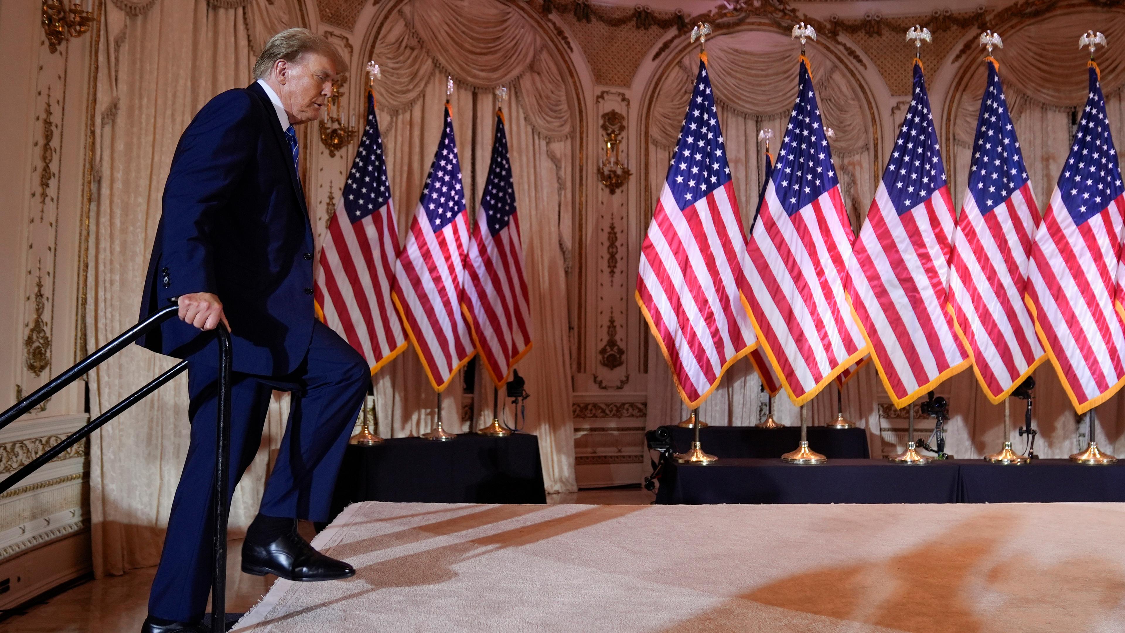 Der ehemalige US-Präsident Donald Trump betritt eine Bühne auf der viele US-Flaggen aufgestellt sind. 
