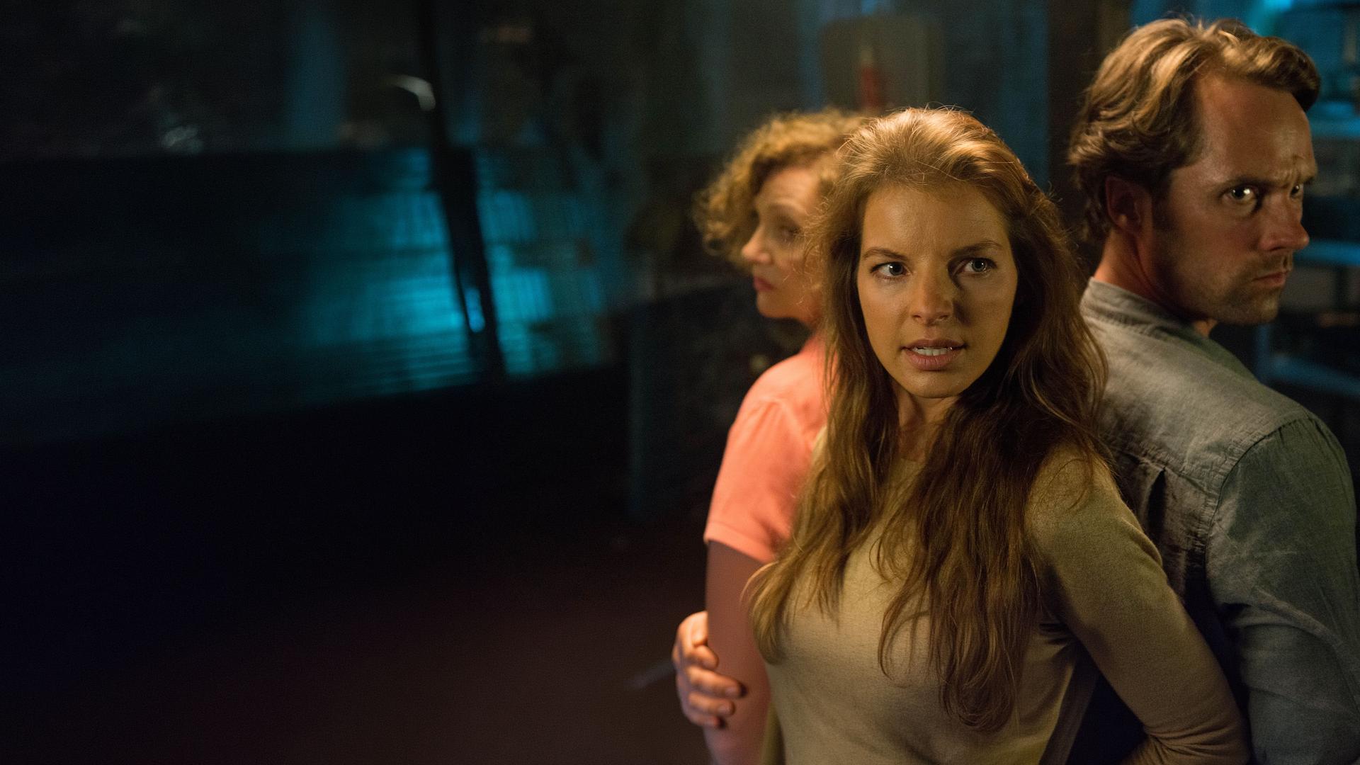 Johanna (Yvonne Catterfeld, links vorne), Tante Finchen (Gila von Weitershausen, links hinten) und Max (Matthias Schloo) stehen Rücken an Rücken in einem dunklen Raum. Johanna und Max schauen mit besorgtem Gesichtsausdruck nach rechts. Im Hintergrund sind unscharf Regale zu erkennen.