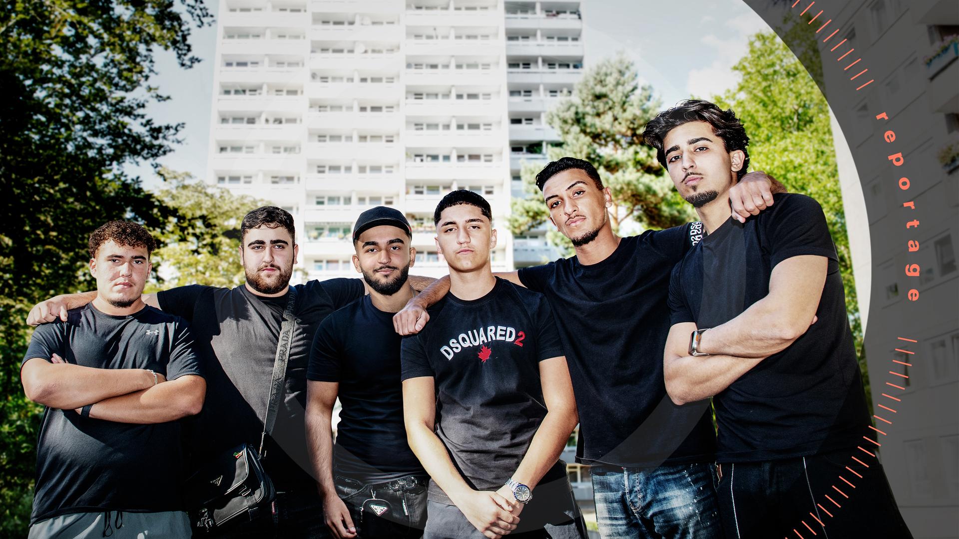 Eine Gruppe von sechs jungen Männern posiert vor einem Hochhaus.