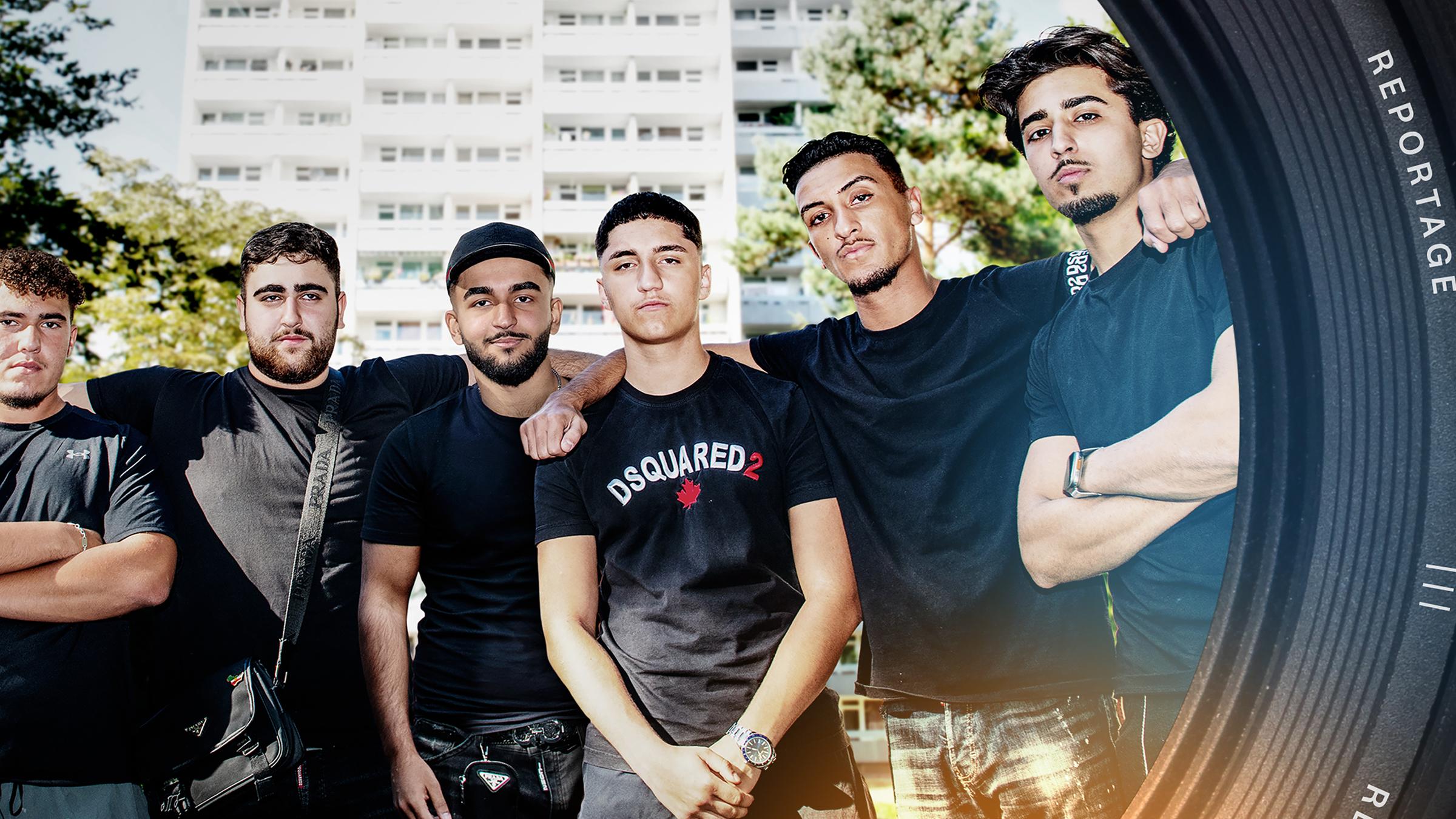 Eine Gruppe von sechs jungen Männern posiert vor einem Hochhaus.