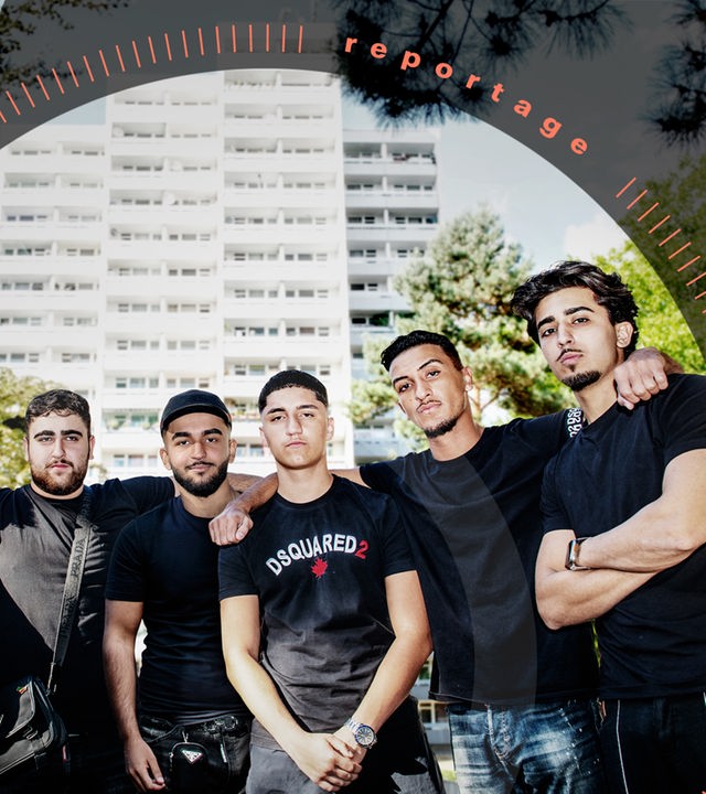 Eine Gruppe von sechs jungen Männern posiert vor einem Hochhaus.