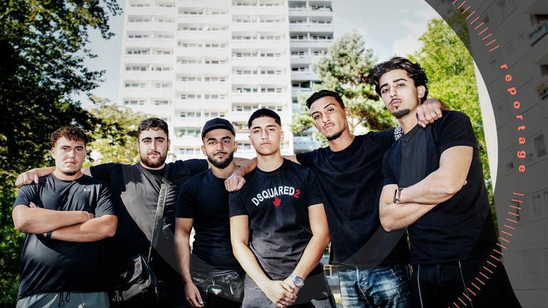 Eine Gruppe von sechs jungen Männern posiert vor einem Hochhaus.